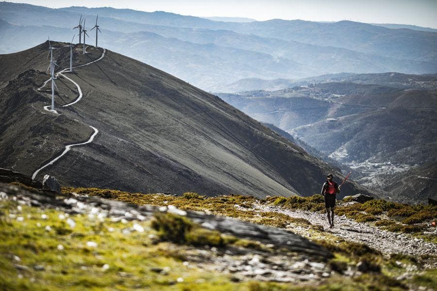 Atleta di trail running in cima alla montagna con pale eoliche