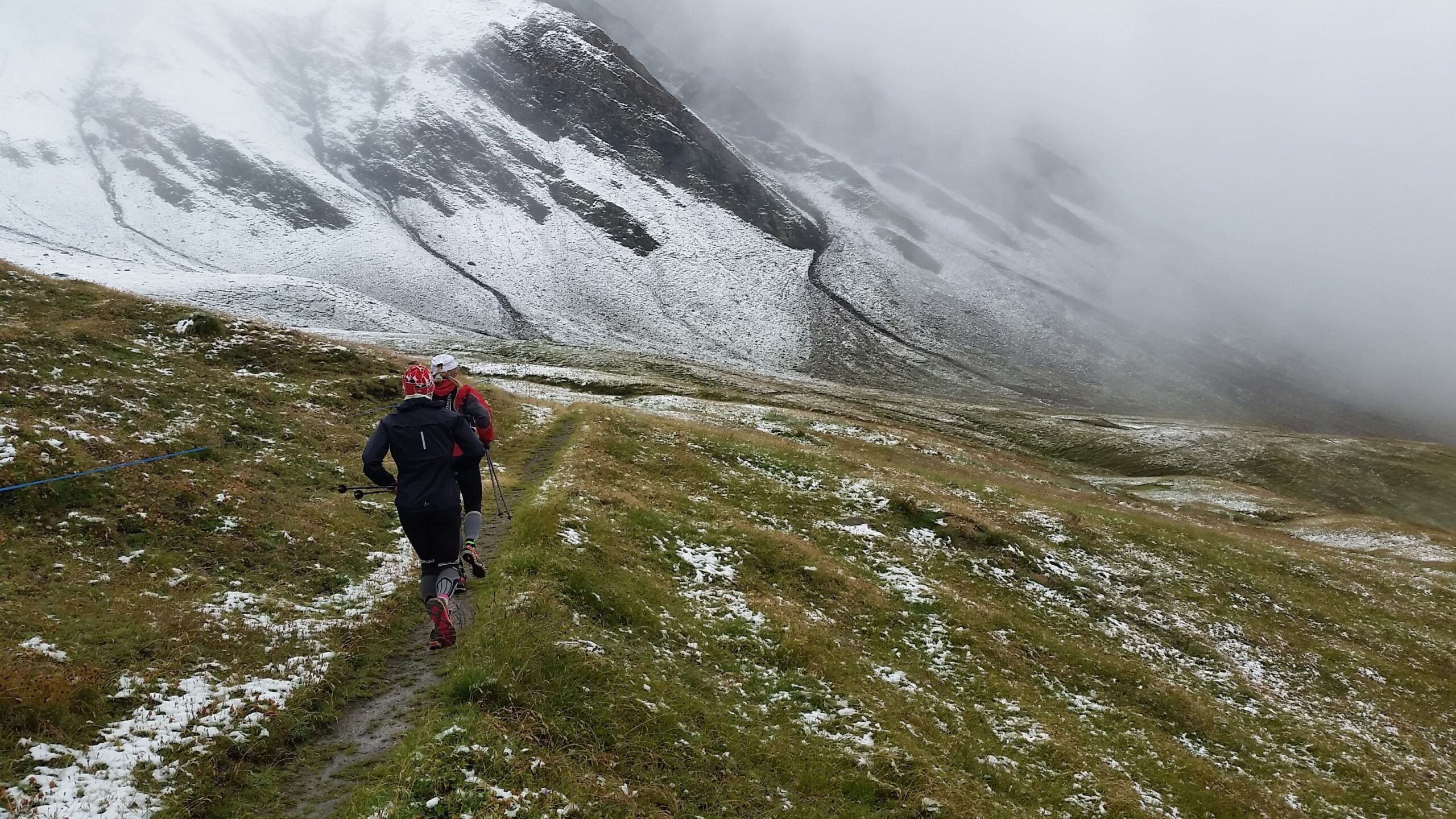 TOR des Geants tratto in discesa con neve e due trail runners 