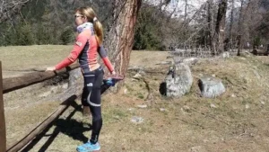 trail runner che fa stretching in montagna